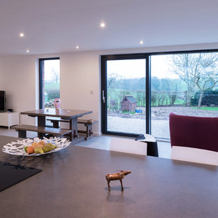 This is an example of a contemporary galley eat-in kitchen in Manchester with an integrated sink, flat-panel cabinets, black cabinets, laminate benchtops, stainless steel appliances, ceramic floors and with island.