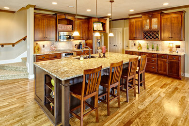 Elegant l-shaped kitchen photo in Kansas City with medium tone wood cabinets, beige backsplash and stainless steel appliances