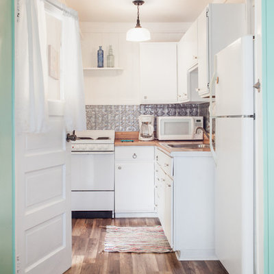 Small beach style galley vinyl floor kitchen photo in Tampa with a drop-in sink, flat-panel cabinets, laminate countertops, metallic backsplash, metal backsplash and white appliances