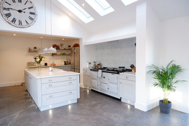 Photo of a large contemporary open plan kitchen in Other with a belfast sink, shaker cabinets, grey cabinets, quartz worktops, glass sheet splashback, coloured appliances, an island, grey floors and white worktops.