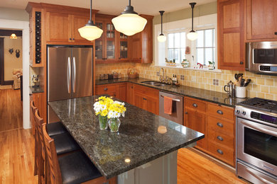Aménagement d'une cuisine classique en L et bois brun avec un évier 2 bacs, un placard à porte shaker, une crédence jaune et un électroménager en acier inoxydable.
