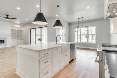 Transitional medium tone wood floor open concept kitchen photo in Oklahoma City with a farmhouse sink, shaker cabinets, white cabinets, quartz countertops, stainless steel appliances and an island