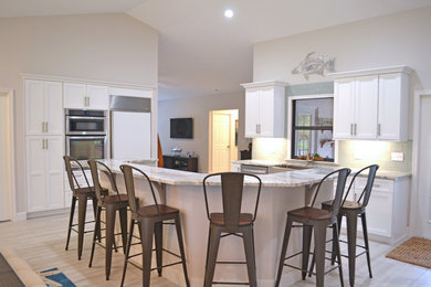 マイアミにある高級な広いコンテンポラリースタイルのおしゃれなキッチン (アンダーカウンターシンク、落し込みパネル扉のキャビネット、白いキャビネット、御影石カウンター、緑のキッチンパネル、ガラスタイルのキッチンパネル、シルバーの調理設備、ラミネートの床、グレーの床、マルチカラーのキッチンカウンター) の写真
