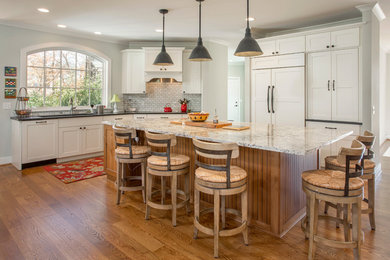 Inspiration for a large transitional l-shaped medium tone wood floor and brown floor eat-in kitchen remodel in Cincinnati with shaker cabinets, white cabinets, granite countertops, gray backsplash, stone tile backsplash, paneled appliances, an island and a double-bowl sink