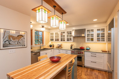 Inspiration for a craftsman u-shaped medium tone wood floor and brown floor kitchen remodel in Seattle with an undermount sink, shaker cabinets, white cabinets, beige backsplash, stainless steel appliances, an island and gray countertops