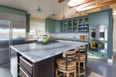 Inspiration for a mid-sized timeless l-shaped concrete floor open concept kitchen remodel in Seattle with a farmhouse sink, glass-front cabinets, green cabinets, wood countertops, gray backsplash, ceramic backsplash, stainless steel appliances and an island