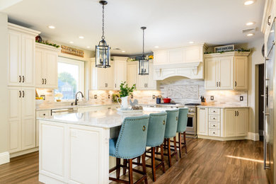 Example of a mid-sized classic l-shaped medium tone wood floor and brown floor eat-in kitchen design in New York with a drop-in sink, raised-panel cabinets, yellow cabinets, quartz countertops, multicolored backsplash, stainless steel appliances, an island and multicolored countertops