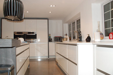 Immagine di una grande cucina moderna con lavello integrato, ante lisce, ante bianche, top in quarzite, elettrodomestici in acciaio inossidabile e pavimento con piastrelle in ceramica