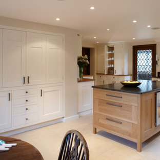 Design ideas for a large traditional l-shaped eat-in kitchen in Surrey with shaker cabinets, light wood cabinets, granite benchtops, black splashback, stainless steel appliances, limestone floors and with island.