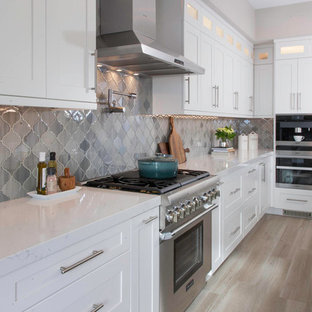 Large transitional kitchen in San Diego with an undermount sink, white cabinets, quartz benchtops, grey splashback, glass tile splashback, stainless steel appliances, light hardwood floors, with island, beige floor, white benchtop and shaker cabinets.