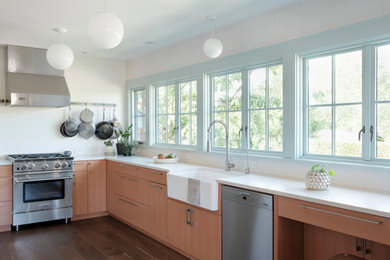 シアトルにあるトランジショナルスタイルのおしゃれなL型キッチン (白いキッチンパネル、シルバーの調理設備、白いキッチンカウンター、エプロンフロントシンク、フラットパネル扉のキャビネット、中間色木目調キャビネット、濃色無垢フローリング、茶色い床) の写真