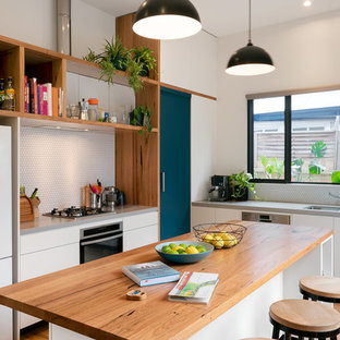 Design ideas for a mid-sized contemporary single-wall kitchen in Melbourne with an undermount sink, flat-panel cabinets, white cabinets, wood benchtops, white splashback, mosaic tile splashback, stainless steel appliances, medium hardwood floors, with island and grey benchtop.