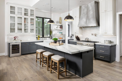 Inspiration for a large transitional l-shaped laminate floor and gray floor eat-in kitchen remodel in Houston with gray cabinets, white backsplash, stainless steel appliances, an island, a farmhouse sink, shaker cabinets, stone slab backsplash and gray countertops