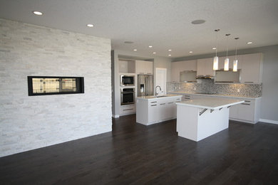 Inspiration for a large contemporary galley medium tone wood floor open concept kitchen remodel in Calgary with a double-bowl sink, white cabinets, quartzite countertops, metallic backsplash, porcelain backsplash, stainless steel appliances and two islands
