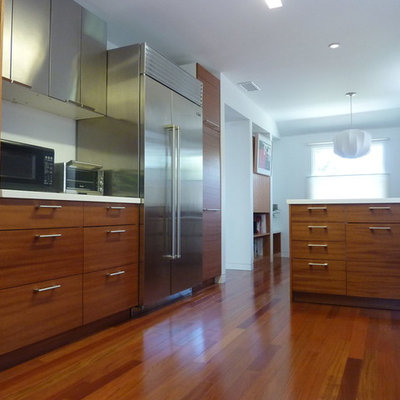 Inspiration for a contemporary u-shaped enclosed kitchen remodel in Los Angeles with flat-panel cabinets, medium tone wood cabinets, solid surface countertops and stainless steel appliances