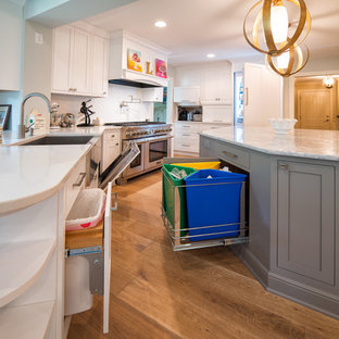 Large contemporary enclosed kitchen designs - Large trendy galley light wood floor enclosed kitchen photo in Minneapolis with a farmhouse sink, shaker cabinets, white cabinets, quartz countertops, white backsplash, glass tile backsplash, stainless steel appliances and an island