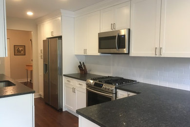 Example of a mid-sized trendy medium tone wood floor eat-in kitchen design in Philadelphia with an undermount sink, shaker cabinets, white cabinets, granite countertops, white backsplash, subway tile backsplash, stainless steel appliances and a peninsula