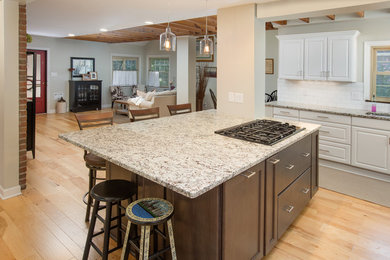 Inspiration for a large farmhouse l-shaped light wood floor enclosed kitchen remodel in Columbus with an undermount sink, raised-panel cabinets, white cabinets, granite countertops, white backsplash, subway tile backsplash, stainless steel appliances and an island