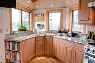Inspiration for a mid-sized transitional u-shaped medium tone wood floor eat-in kitchen remodel in Portland Maine with an undermount sink, raised-panel cabinets, medium tone wood cabinets, granite countertops, gray backsplash, glass tile backsplash, stainless steel appliances and no island