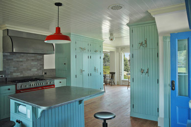 Eat-in kitchen - mid-sized cottage l-shaped medium tone wood floor eat-in kitchen idea in Portland Maine with an undermount sink, beaded inset cabinets, blue cabinets, limestone countertops, gray backsplash, stone slab backsplash, colored appliances and an island