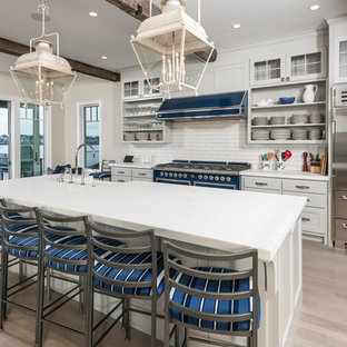 Photo of a beach style kitchen in Boston with open cabinets, with island, white splashback, subway tile splashback, coloured appliances, light hardwood floors, beige floor and white benchtop.