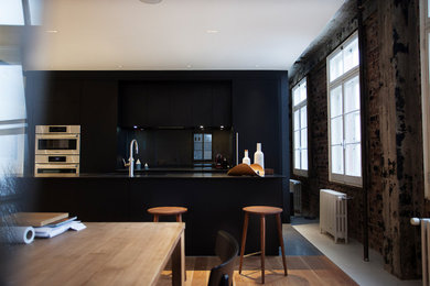 Kitchen - kitchen idea in Montreal with flat-panel cabinets, black cabinets, quartzite countertops and an island