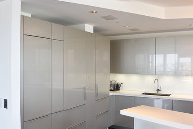 Example of a large minimalist l-shaped marble floor eat-in kitchen design in Miami with an undermount sink, flat-panel cabinets, gray cabinets, quartz countertops, white backsplash, glass sheet backsplash, stainless steel appliances and an island