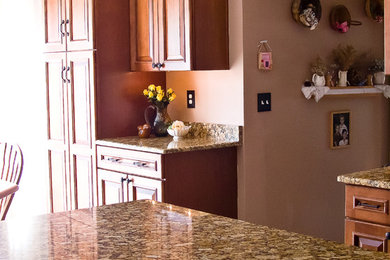 Example of a classic l-shaped eat-in kitchen design in Philadelphia with raised-panel cabinets, medium tone wood cabinets, granite countertops and an island
