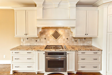 Diseño de cocina clásica con puertas de armario blancas, encimera de granito, salpicadero multicolor, salpicadero de azulejos de piedra, electrodomésticos de acero inoxidable y una isla
