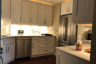Mid-sized trendy l-shaped medium tone wood floor and brown floor enclosed kitchen photo in Chicago with shaker cabinets, white cabinets, white backsplash, no island, white countertops, subway tile backsplash, an undermount sink and stainless steel appliances