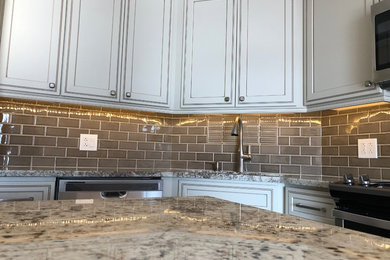 Kitchen - mid-sized contemporary u-shaped vinyl floor and brown floor kitchen idea in Chicago with an undermount sink, beige cabinets, granite countertops, brown backsplash, subway tile backsplash, stainless steel appliances, an island and multicolored countertops
