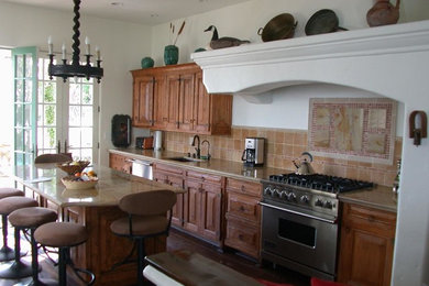ロサンゼルスにある広いモダンスタイルのおしゃれなキッチン (中間色木目調キャビネット、ベージュキッチンパネル、シルバーの調理設備) の写真