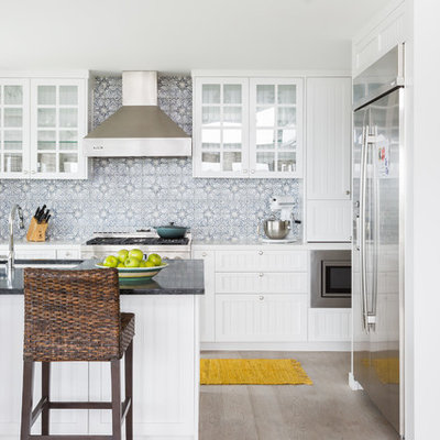 Open concept kitchen - mid-sized coastal l-shaped light wood floor and beige floor open concept kitchen idea in Los Angeles with an undermount sink, white cabinets, gray backsplash, stainless steel appliances, an island, quartzite countertops, cement tile backsplash, white countertops and recessed-panel cabinets