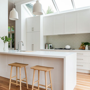 Mid-sized contemporary galley eat-in kitchen in Melbourne with shaker cabinets, white cabinets, quartzite benchtops, ceramic splashback, light hardwood floors, white benchtop, an undermount sink, panelled appliances, a peninsula, beige floor and vaulted.