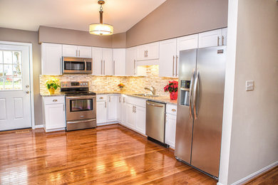 Photo of a medium sized classic l-shaped open plan kitchen in DC Metro with a double-bowl sink, shaker cabinets, white cabinets, granite worktops, grey splashback, mosaic tiled splashback, stainless steel appliances and medium hardwood flooring.