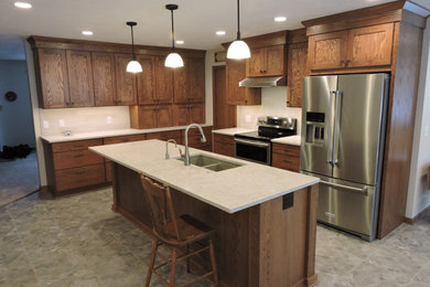 Inspiration for a large craftsman l-shaped vinyl floor and gray floor eat-in kitchen remodel in Other with an undermount sink, shaker cabinets, dark wood cabinets, quartzite countertops, gray backsplash, ceramic backsplash, stainless steel appliances, an island and gray countertops