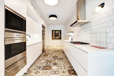 Enclosed kitchen - small contemporary galley porcelain tile enclosed kitchen idea in New York with an undermount sink, flat-panel cabinets, white cabinets, solid surface countertops, white backsplash, porcelain backsplash, stainless steel appliances and no island