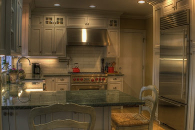 Idéer för ett mellanstort klassiskt kök, med en rustik diskho, luckor med infälld panel, vita skåp, granitbänkskiva, vitt stänkskydd, stänkskydd i tunnelbanekakel, rostfria vitvaror, mellanmörkt trägolv och en halv köksö