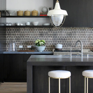 Inspiration for a beach style kitchen in Los Angeles with an integrated sink, flat-panel cabinets, black cabinets, soapstone benchtops, multi-coloured splashback, ceramic splashback, black appliances, light hardwood floors and with island.