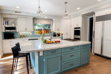 Example of a large beach style l-shaped light wood floor and multicolored floor open concept kitchen design in Los Angeles with a farmhouse sink, beaded inset cabinets, white cabinets, quartz countertops, blue backsplash, glass tile backsplash, stainless steel appliances and an island