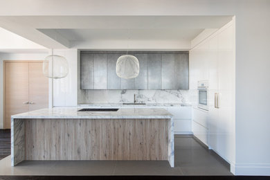 Example of a mid-sized trendy l-shaped porcelain tile and gray floor eat-in kitchen design in New York with an undermount sink, flat-panel cabinets, white backsplash, an island and white countertops