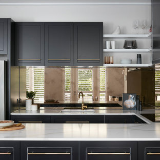Photo of a large contemporary u-shaped kitchen in Melbourne with black cabinets, marble benchtops, metallic splashback, a double-bowl sink, raised-panel cabinets, glass tile splashback, coloured appliances, plywood floors, with island, brown floor and white benchtop.