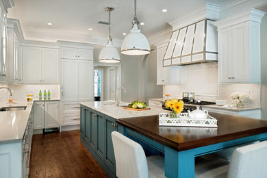 Klassisk inredning av ett stort vit vitt kök, med träbänkskiva, en köksö, en undermonterad diskho, luckor med infälld panel, blå skåp, vitt stänkskydd, integrerade vitvaror, mellanmörkt trägolv och brunt golv