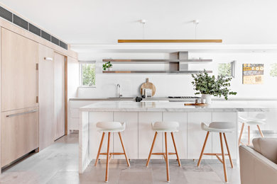 Moderne Küche in L-Form mit Unterbauwaschbecken, flächenbündigen Schrankfronten, weißen Schränken, Küchengeräten aus Edelstahl, Kücheninsel, grauem Boden und weißer Arbeitsplatte in Sydney