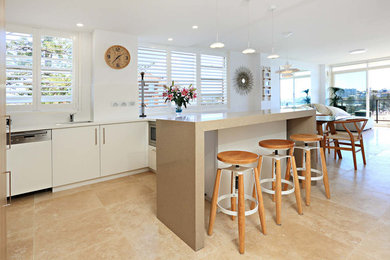 Modern inredning av ett litet kök, med släta luckor, vita skåp, bänkskiva i koppar, glaspanel som stänkskydd och en halv köksö