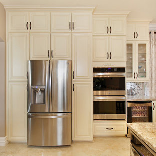 Photo of a large traditional u-shaped open plan kitchen in Miami with an undermount sink, raised-panel cabinets, beige cabinets, quartz benchtops, multi-coloured splashback, mosaic tile splashback, stainless steel appliances, porcelain floors, a peninsula and beige floor.