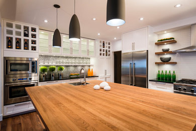 Mid-sized transitional l-shaped brown floor eat-in kitchen photo in Ottawa with a single-bowl sink, shaker cabinets, white cabinets, wood countertops, white backsplash, glass sheet backsplash, stainless steel appliances, an island and black countertops