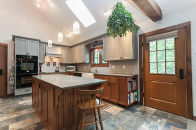 Kitchen - traditional l-shaped multicolored floor kitchen idea in Bridgeport with a farmhouse sink, recessed-panel cabinets, gray cabinets, gray backsplash, subway tile backsplash, black appliances, an island and gray countertops