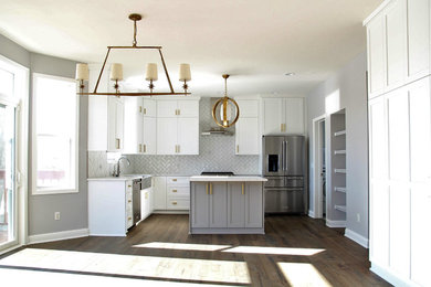 Example of a mid-sized trendy u-shaped dark wood floor and brown floor open concept kitchen design in Minneapolis with a farmhouse sink, shaker cabinets, white cabinets, marble countertops, white backsplash, subway tile backsplash, stainless steel appliances, an island and white countertops