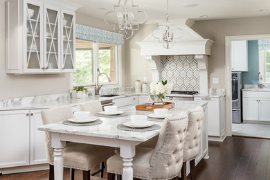 Inspiration for a large traditional u-shaped kitchen in Louisville with a submerged sink, glass-front cabinets, white cabinets, marble worktops, stainless steel appliances, medium hardwood flooring, an island and brown floors.